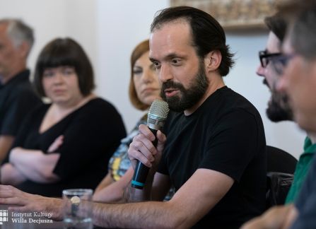 fotografia. spotkanie literacki środek europy w ramach festiwalu art piknik w willi decjusza. zaproszeni goście dyskutują przy długim stole w sali marceliny czartoryskiej. Ferenc Czinki mówi do mikrofonu.